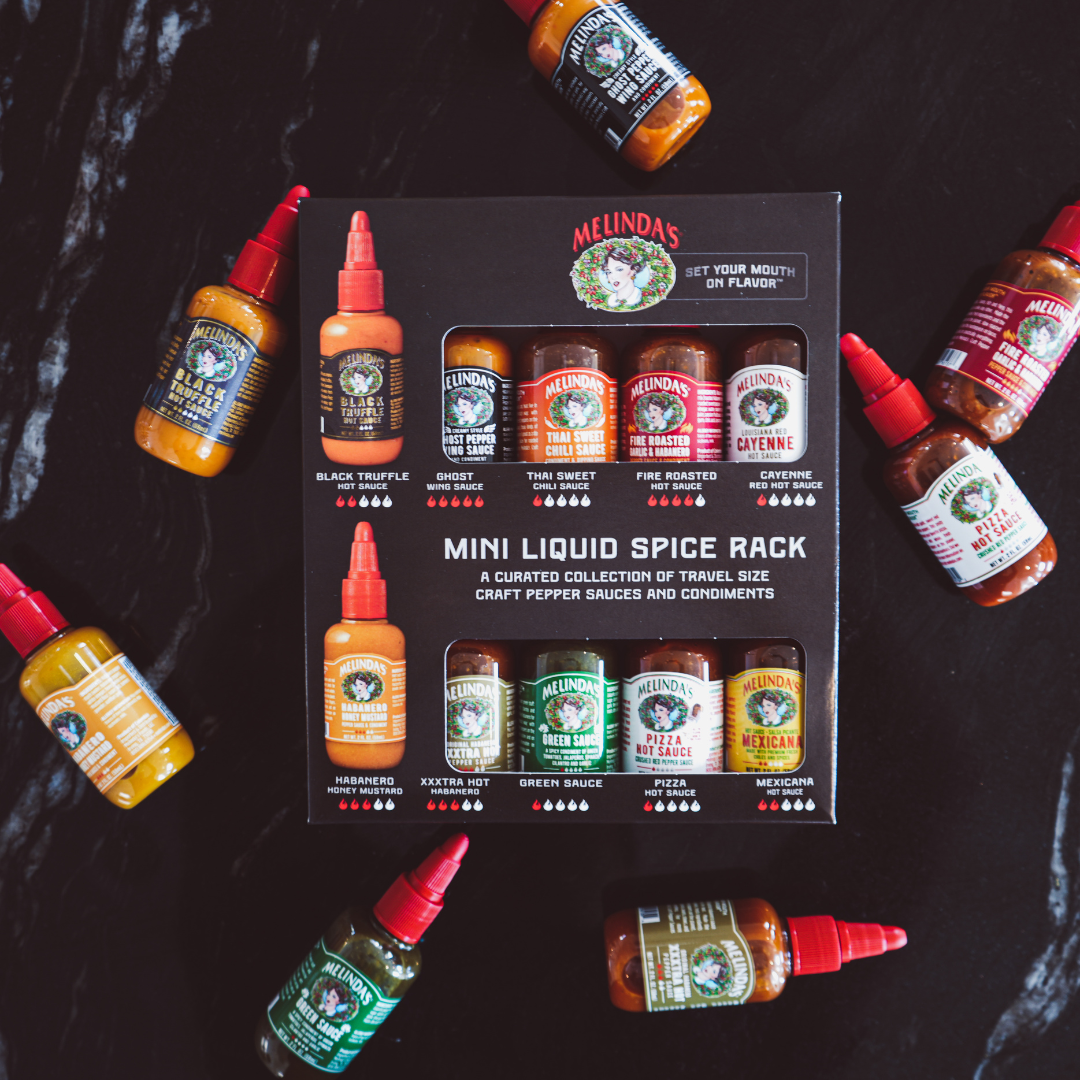 Melinda's Mini Liquid Spice Rack gift set with 10 travel-size hot sauces and condiments surrounded by individual bottles