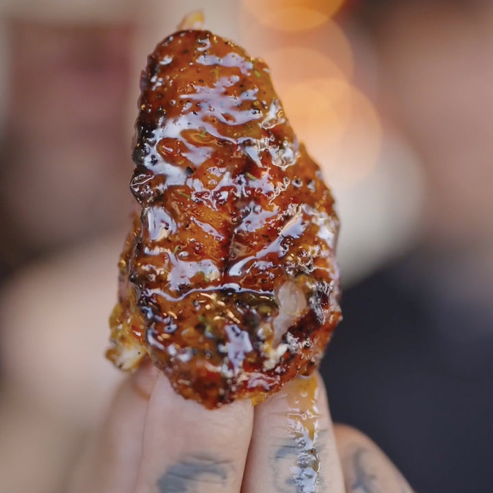 Hand holding a piece of raw honeycomb dripping with golden honey