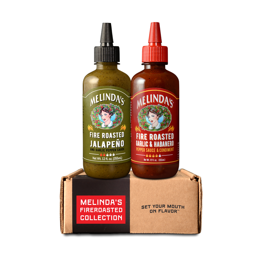 Two bottles of Melinda's Fire Roasted hot sauce in green and red packaging on a branded cardboard box