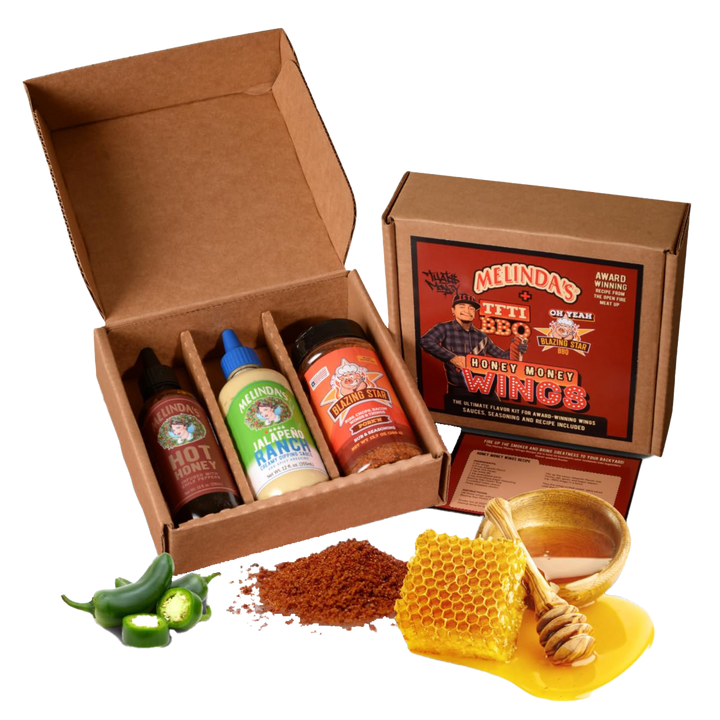Melinda's BBQ gift set with sauces and seasonings in open cardboard box, alongside fresh jalapeños, spices, and honeycomb