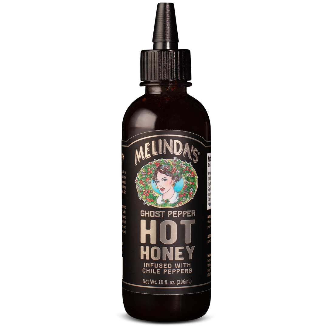 Dark amber glass bottle with dropper cap of Melinda's Ghost Pepper Hot Honey, featuring vintage-style label with woman's...