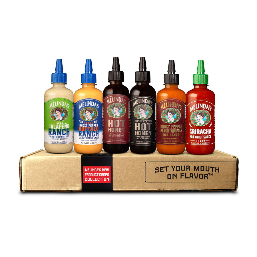 Six bottles of Melinda's hot sauce varieties displayed on a cardboard box labeled "SET YOUR MOUTH ON FLAVOR"