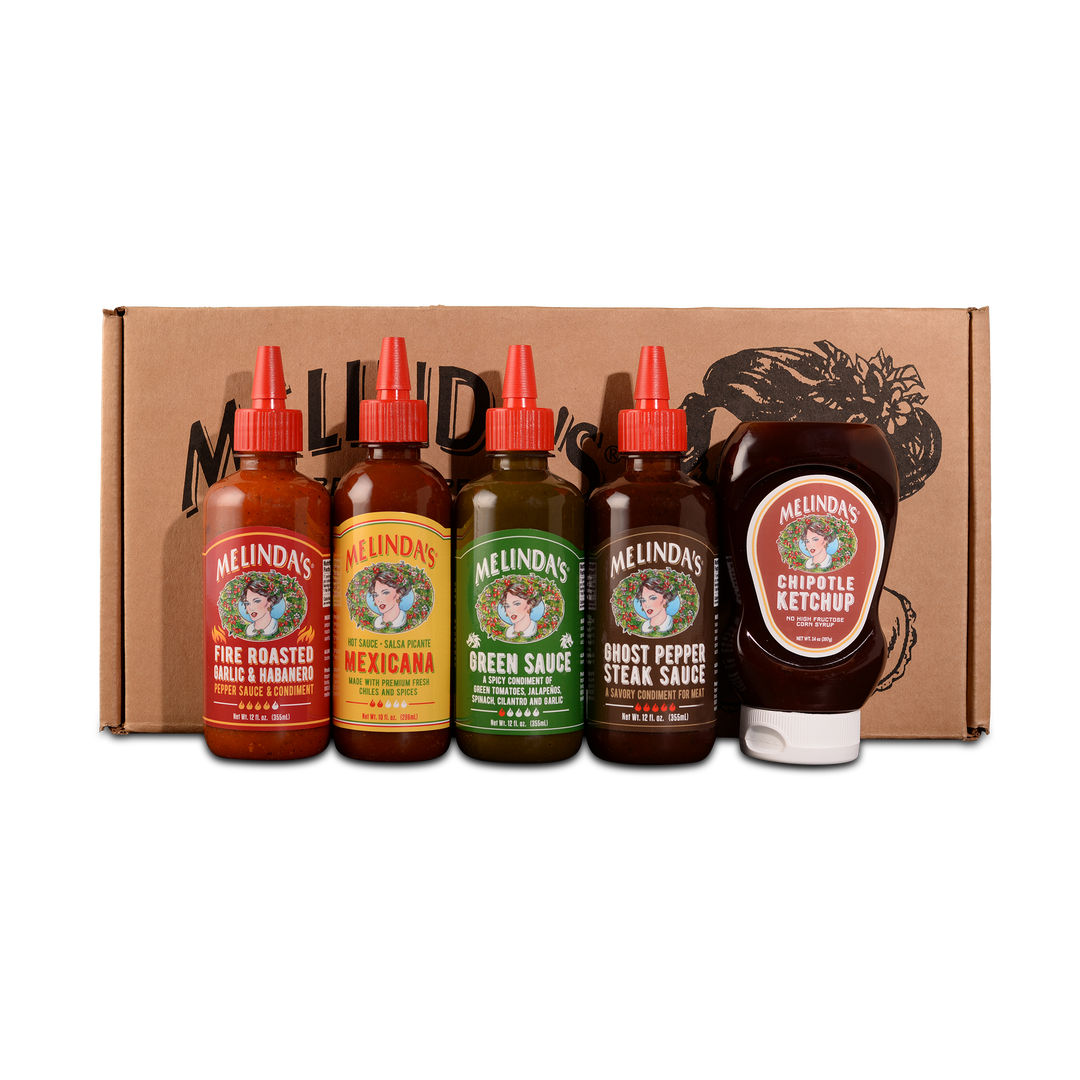 Five Melinda's hot sauce bottles with red caps and one chipotle ketchup bottle displayed in front of brown cardboard box
