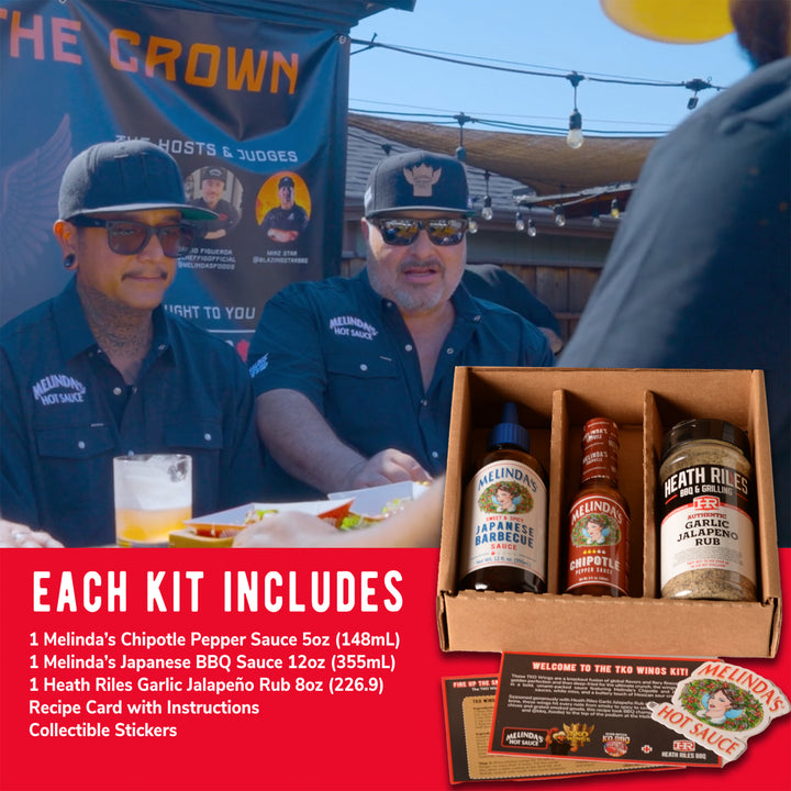 Two men in matching uniforms stand behind a food booth next to a sauce kit containing three bottles and recipe cards.