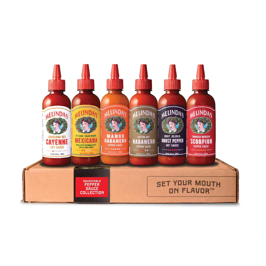 Six Melinda's hot sauce bottles in different flavors displayed on cardboard box with "Set Your Mouth on Flavor" text