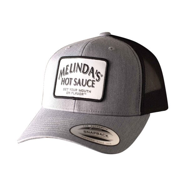 Gray and black snapback trucker hat with white Melinda's Hot Sauce logo patch reading "Set Your Mouth on Flavor"