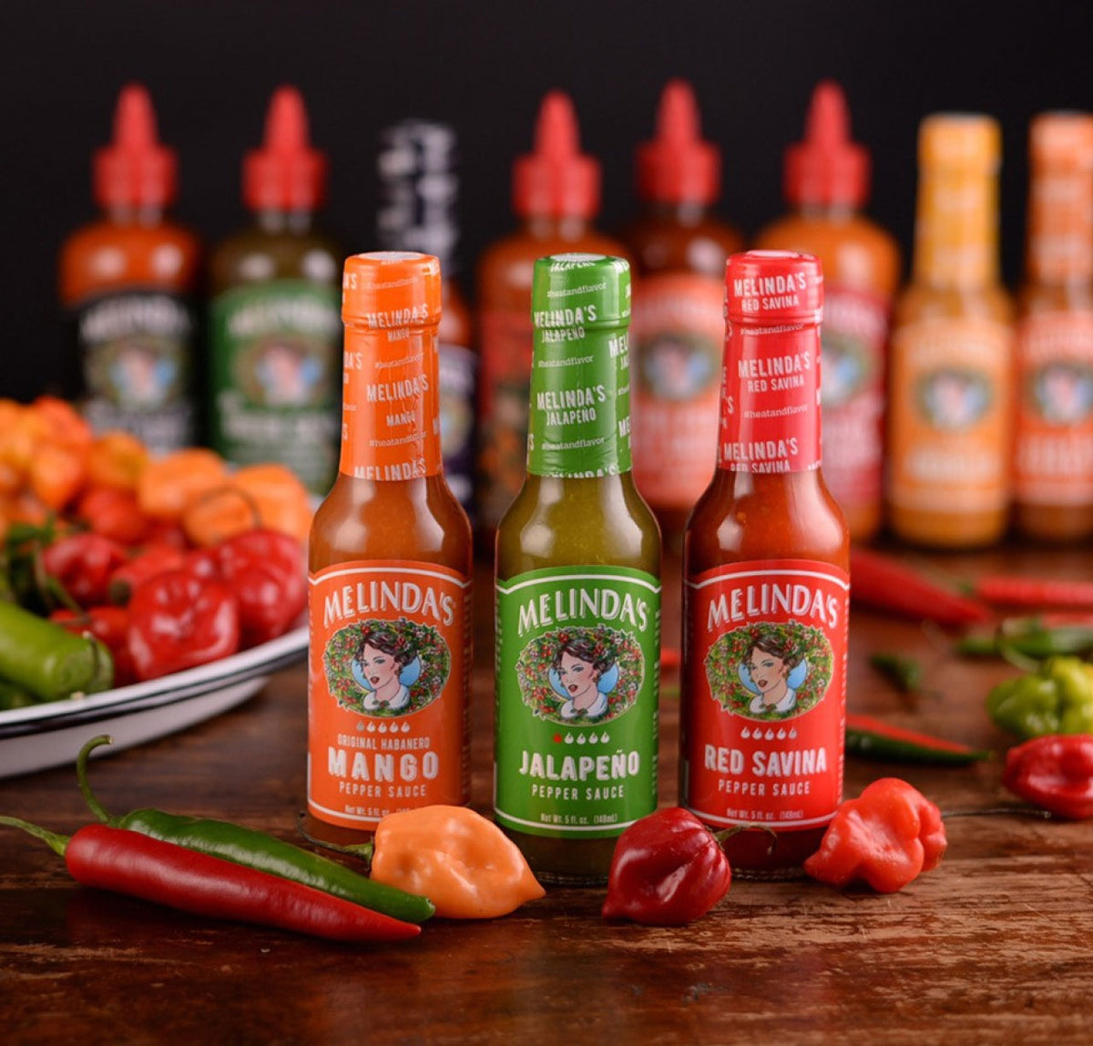 Three Melinda's hot sauce bottles in orange, green, and red featuring Mango, Jalapeño, and Red Savina flavors with fresh...