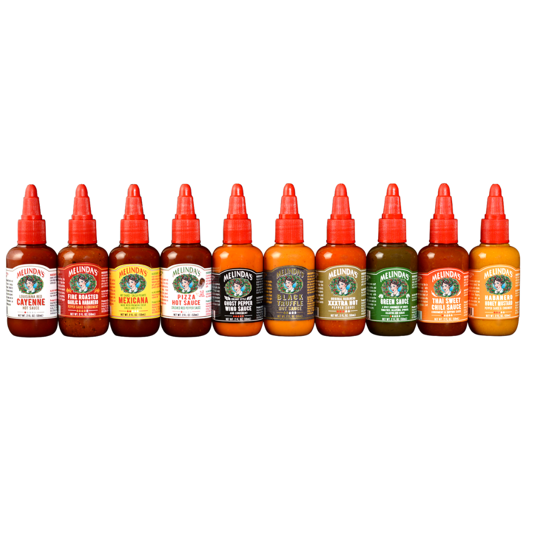 Ten Melinda's hot sauce bottles in a row with red caps, featuring various flavors like Cayenne, Fire Roasted Garlic, and...