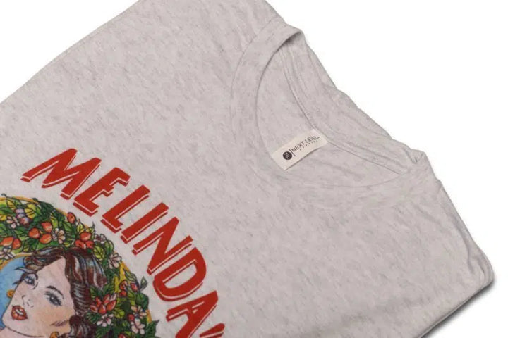 Light gray t-shirt with "MELINDA'S" text in red letters and colorful illustration of woman with flowers in her hair